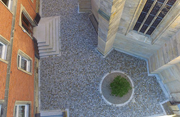 Drohnenansicht auf gepflasterten Eingangsbereich mit Bauminsel