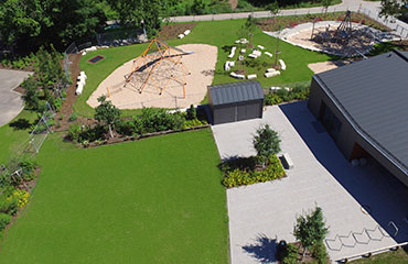 Drohnenansicht auf Rasen- und Sandfläche mit Klettergerüst