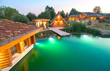 Holzblockhäuser am Pool mit Abendbeleuchtung